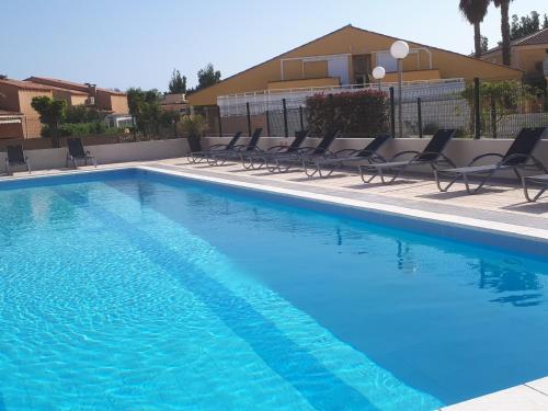 une grande piscine avec des chaises et un bâtiment dans l'établissement Port Soleil Naturiste, au Cap d'Agde