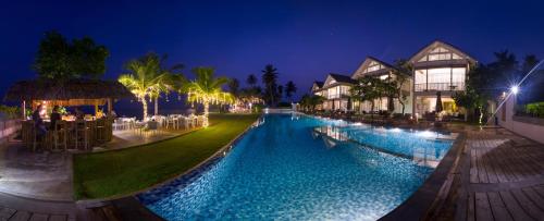 a swimming pool in front of a resort at night at Sri Sharavi Beach Villas & Spa - with 43 metre saltwater infinity pool in Mirissa