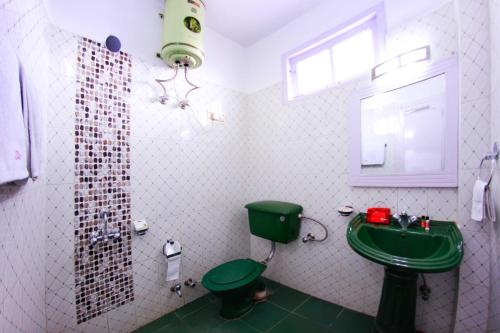 a bathroom with a green toilet and a green sink at Hotel Ekant in Chail