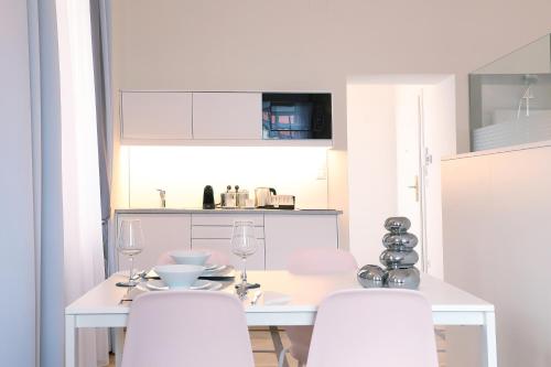 a white kitchen with a white table and white chairs at Stylische Cityapartments Benedikt in Klagenfurt