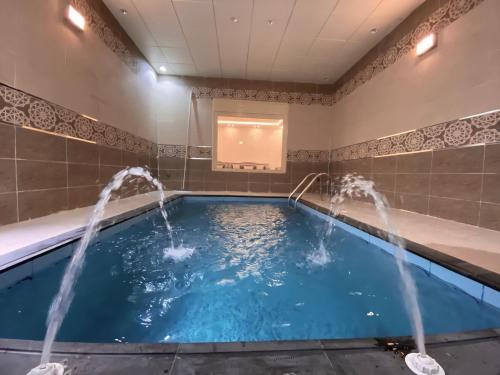 a pool with water fountains in a room at Taif promise Chalets in Taif