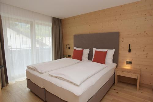 een slaapkamer met een groot wit bed met rode kussens bij Appartments Hopfgartner Eurospar in Lutago