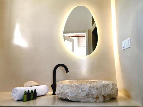 uma casa de banho com um lavatório de pedra e um espelho. em Avra Pahainas em Pachaina