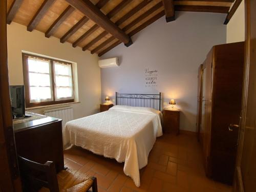 a bedroom with a white bed and a window at Agriturismo Tenuta Badia in Paciano