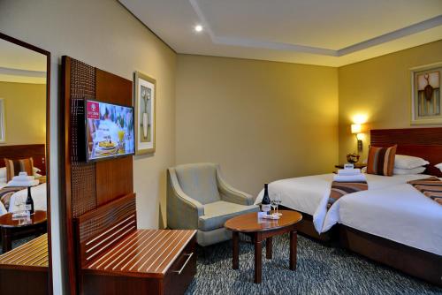 a hotel room with two beds and a chair at City Lodge Hotel Fourways in Johannesburg