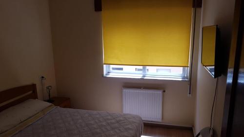 a bedroom with a bed and a window with a yellow curtain at HOSTAL BODEGÓN A COSECHA in San Ciprián