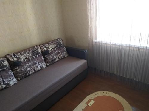 a couch with pillows sitting in a room with a window at Уютная квартира метро Защитников Украины in Kharkiv