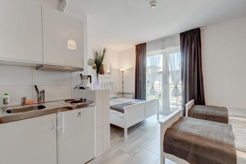 a kitchen with white cabinets and a sink at Pod Winogronem - Apartamenty z basenem i wyżywieniem in Pobierowo
