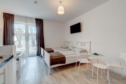 a bedroom with a bed and a table and chairs at Pod Winogronem - Apartamenty z basenem i wyżywieniem in Pobierowo