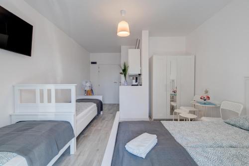 a white bedroom with two beds and a table at Pod Winogronem - Apartamenty z basenem i wyżywieniem in Pobierowo
