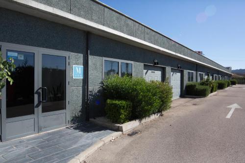 a blue building with a row of doors and bushes at Motel Emporio in Cabezón de Pisuerga
