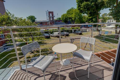 a patio with a table and chairs on a balcony at Pod Winogronem - Apartamenty z basenem i wyżywieniem in Pobierowo