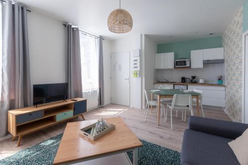 Il comprend un salon avec une télévision et une cuisine avec une table. dans l'établissement Trankil-Apparts Centre 2, à Saint-Quentin