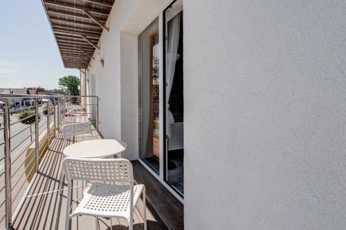 a balcony with chairs and a table on a building at Pod Winogronem - Apartamenty z basenem i wyżywieniem in Pobierowo