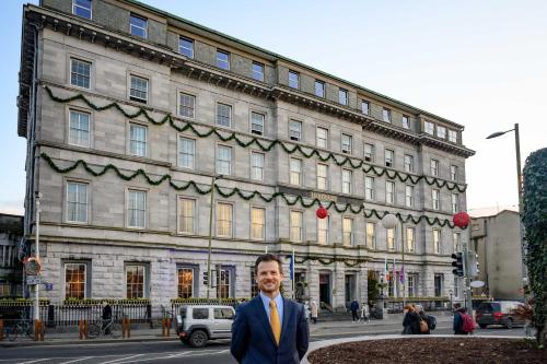 a man in a suit and tie standing in front of a building at The Hardiman (formerly Hotel Meyrick) in Galway