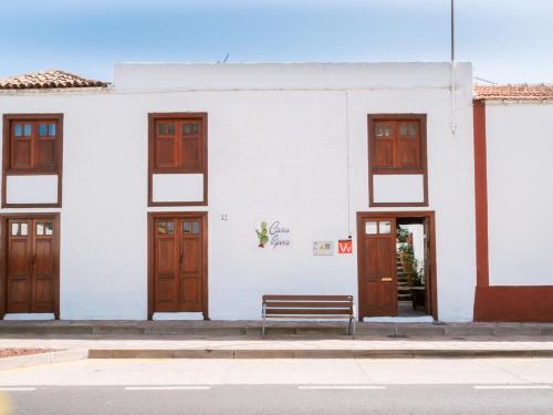 um edifício branco com portas de madeira e um banco em Casa Fina em Santiago del Teide
