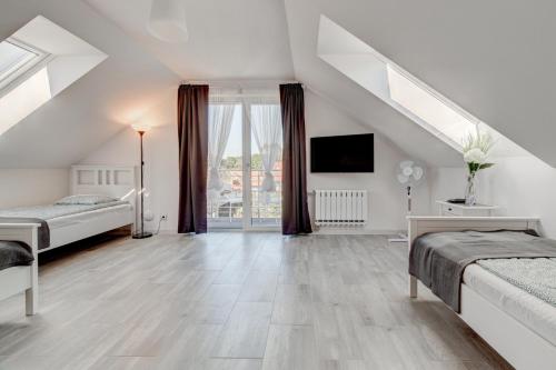 a attic bedroom with two beds and a tv at Pod Winogronem - Apartamenty z basenem i wyżywieniem in Pobierowo