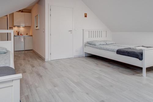 a white room with two beds and a kitchen at Pod Winogronem - Apartamenty z basenem i wyżywieniem in Pobierowo