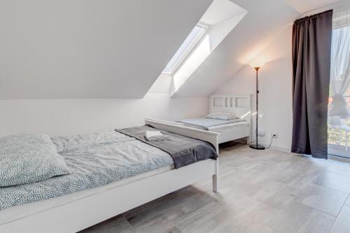 a white bedroom with two beds and a window at Pod Winogronem - Apartamenty z basenem i wyżywieniem in Pobierowo