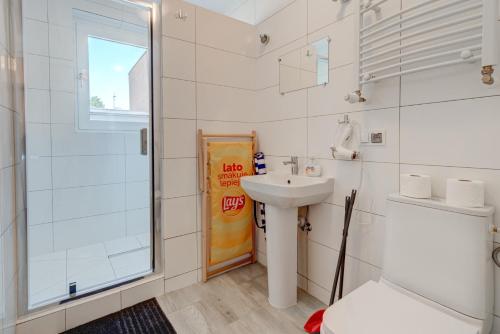a white bathroom with a sink and a shower at Pod Winogronem - Apartamenty z basenem i wyżywieniem in Pobierowo