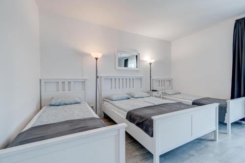 two beds in a white room with a mirror at Pod Winogronem - Apartamenty z basenem i wyżywieniem in Pobierowo
