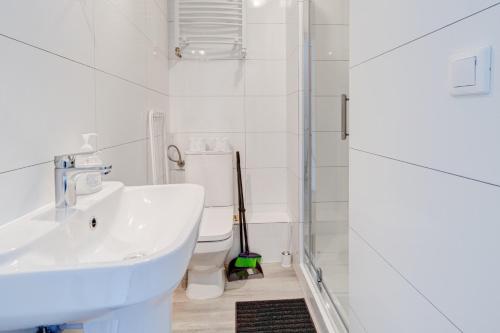 a white bathroom with a sink and a toilet at Pod Winogronem - Apartamenty z basenem i wyżywieniem in Pobierowo