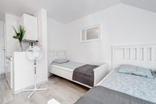 a white bedroom with two beds and a fan at Pod Winogronem - Apartamenty z basenem i wyżywieniem in Pobierowo