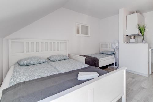 a white bedroom with two beds in it at Pod Winogronem - Apartamenty z basenem i wyżywieniem in Pobierowo