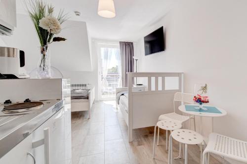 a kitchen with white cabinets and a table and chairs at Pod Winogronem - Apartamenty z basenem i wyżywieniem in Pobierowo