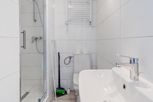 a white bathroom with a shower and a sink at Pod Winogronem - Apartamenty z basenem i wyżywieniem in Pobierowo