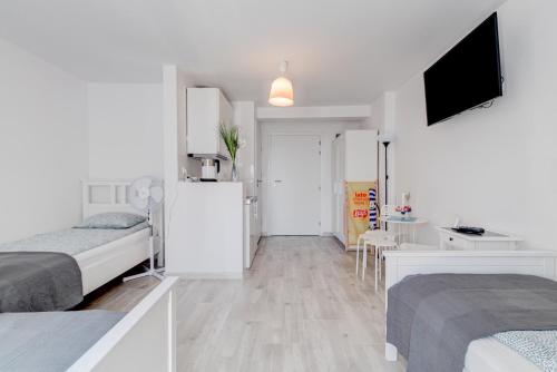 a white bedroom with two beds and a refrigerator at Pod Winogronem - Apartamenty z basenem i wyżywieniem in Pobierowo