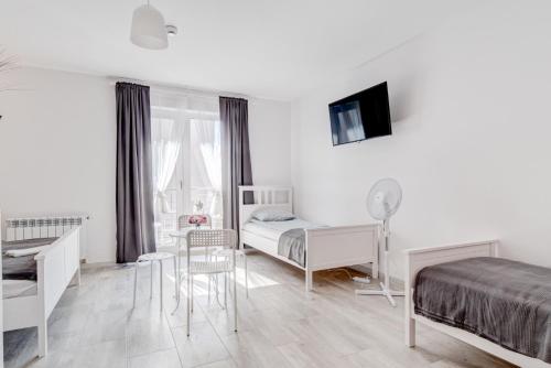 a white bedroom with a bed and a desk and a table at Pod Winogronem - Apartamenty z basenem i wyżywieniem in Pobierowo