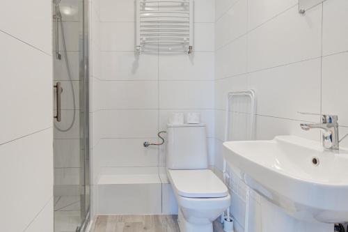 a white bathroom with a toilet and a sink at Pod Winogronem - Apartamenty z basenem i wyżywieniem in Pobierowo
