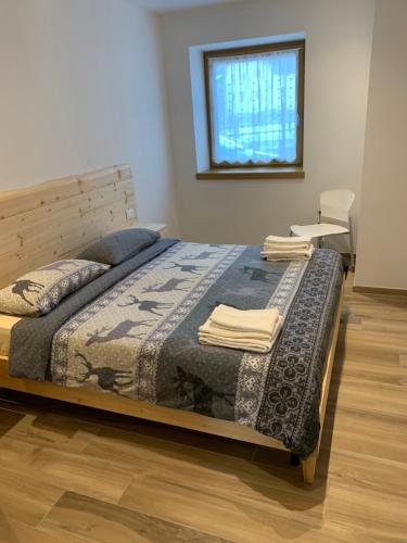 a bedroom with a bed with a blanket and a chair at Ciasa De Rosa in Pozza di Fassa
