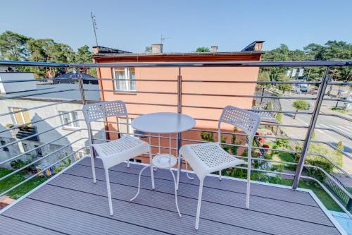 a balcony with two chairs and a table at Pod Winogronem - Apartamenty z basenem i wyżywieniem in Pobierowo