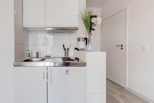 a kitchen with white cabinets and a sink at Pod Winogronem - Apartamenty z basenem i wyżywieniem in Pobierowo
