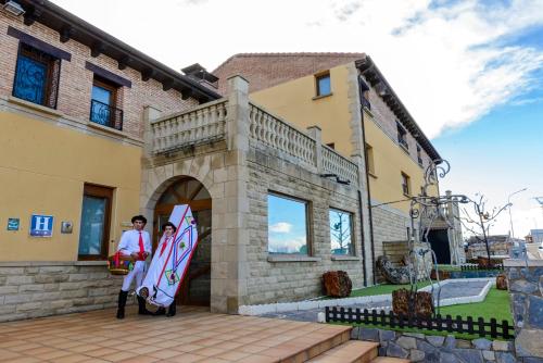 two people standing in front of a building holding a surfboard at Hotel La Barrosa in Abejar