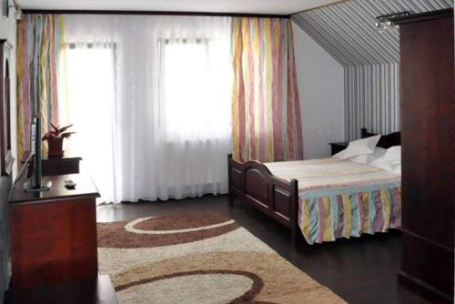 um quarto com uma cama, 2 janelas e um tapete em Pensiunea Filonul de Aur em Aktenburg
