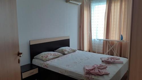 een slaapkamer met een bed met roze lakens en een raam bij Complex Oazis in Ravda