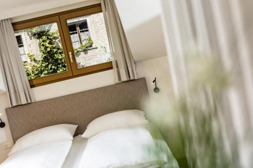 a bedroom with a bed with white pillows and a window at Apartments Seewinkel in Caldaro