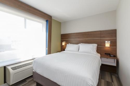 a bedroom with a large white bed and a window at Holiday Inn Express & Suites - South Bend - Notre Dame Univ. in South Bend