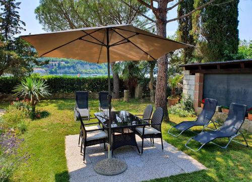 a table and chairs under an umbrella in a yard at Apartment Boreas in Strunjan