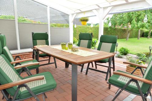 einen Holztisch und Stühle auf einer Terrasse in der Unterkunft Ferienwohnung Sonnenberg, 25502 in Weener