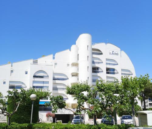 un bâtiment blanc avec des arbres devant dans l'établissement P2 Couchant 2 étoiles La Grande Motte 5 min Plage-Parking privatif, à La Grande Motte
