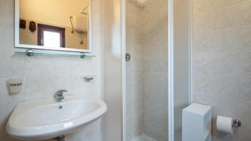 a white bathroom with a sink and a shower at Welcomely - Isole Apartments in Olbia