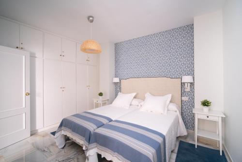 1 dormitorio con 1 cama con manta de rayas azul y blanco en Arco Macarena Suite, en Sevilla