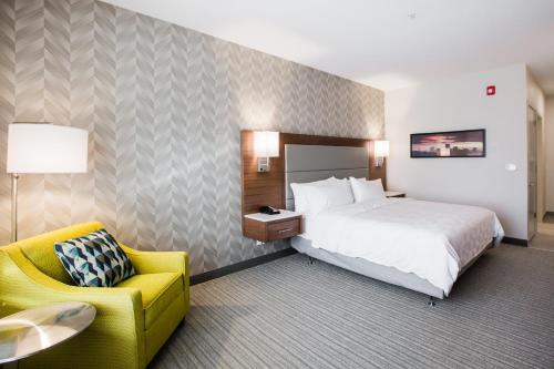 a hotel room with a bed and a yellow chair at Holiday Inn Hotel & Suites Calgary South - Conference Ctr by IHG in Calgary
