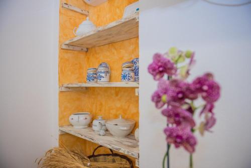 une étagère avec des casseroles et des poêles avec des fleurs violettes dans l'établissement B&B Sa domo de sos Massaios, à Orosei