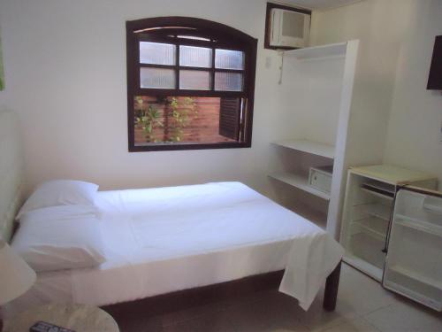 a small bedroom with a bed and a window at Pousada L'étage in Búzios
