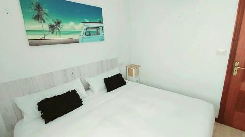 1 dormitorio con 1 cama blanca y 2 almohadas negras en Portonovo Suites by Serendipia Turismo, en Sanxenxo